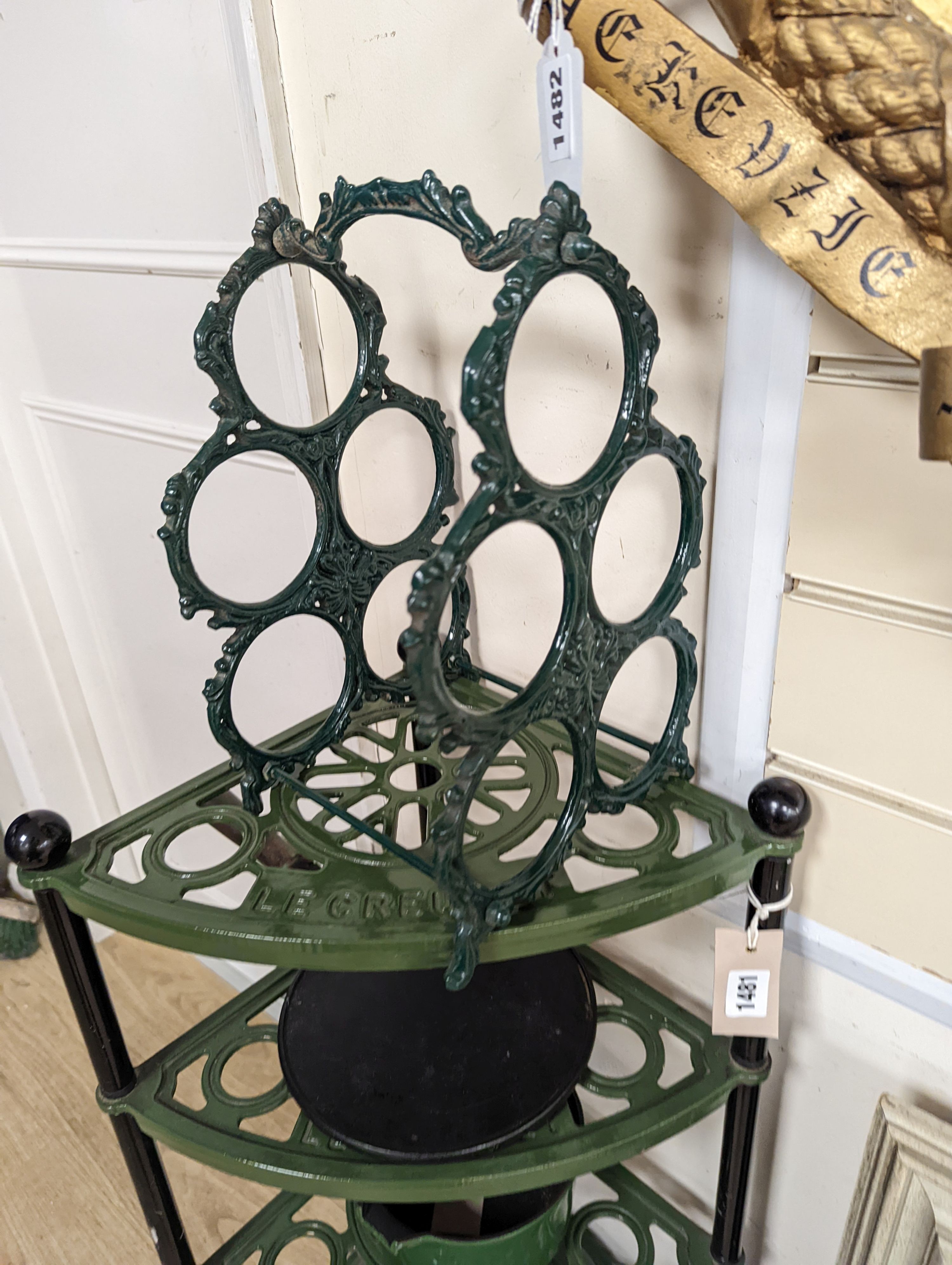 A green enamel Le Cruset pot stand, three pans and a bottle rack, stand 90 cms high.
